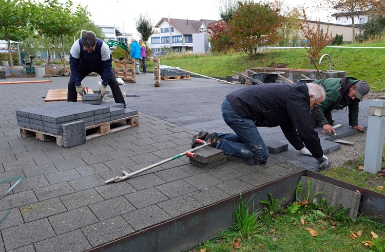 Unter kundiger Leitung von Mitarbeitern der Gartenbau Bernet AG Nottwil verlegen die Rotarier die Steinplatten für den neuen Begegnungsplatz. (Foto Otto Schmid)