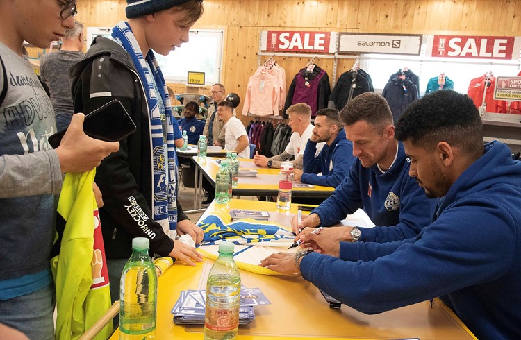 Mohamed Dräger und Christian Gentner (von rechts) unterschreiben eine FCL-Fahne. (Foto Thomas Stillhart)