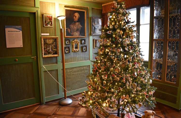 Ein prall gefüllter Christbaum wie aus einem Märchenbuch, dahinter an den Wänden Hinterglasmalereien.  (Foto Livia Kurmann)