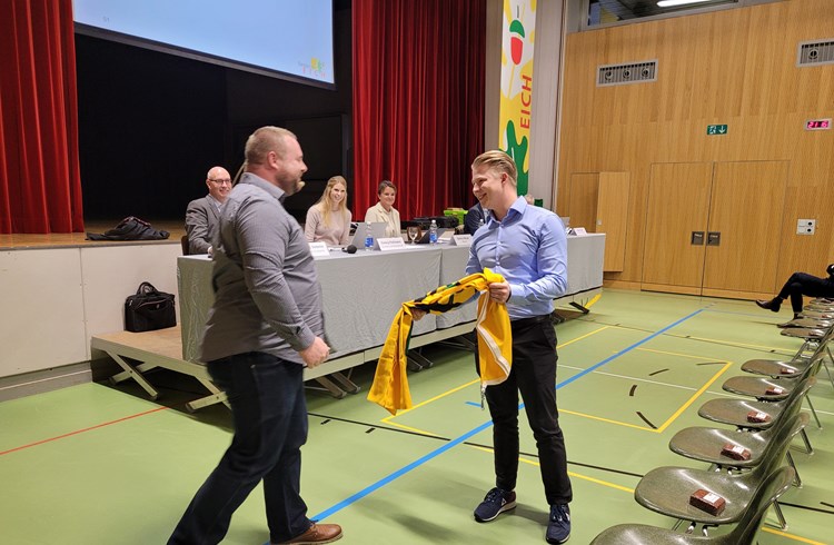 Kilian Frühauf wurde in die Controllingkommission gewählt und erhielt von Gemeindepräsident Adrian Bachmann eine Eicher-Fahne. (Foto Roseline Betschart)