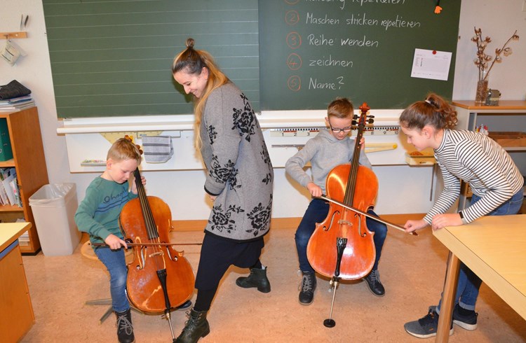 Milena Kowarik und Musikschülerin Dana erklären den Kindern, wie das Cello gespielt wird. Foto ML
